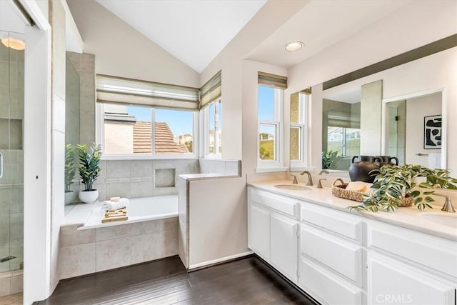 bathroom with a stall shower, vaulted ceiling, a sink, and double vanity