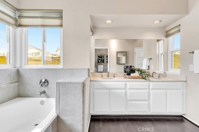 full bath with a garden tub, double vanity, a sink, and a wealth of natural light