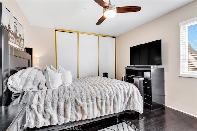 bedroom with dark wood-style floors, a closet, multiple windows, and a ceiling fan