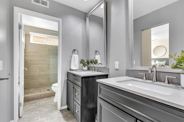 bathroom featuring a shower stall, visible vents, two vanities, and a sink