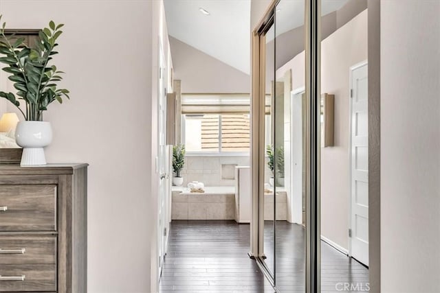 hall with vaulted ceiling and hardwood / wood-style floors