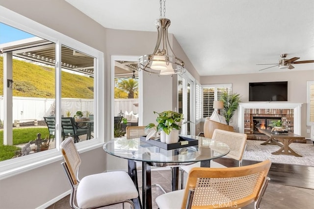 sunroom / solarium featuring a ceiling fan, vaulted ceiling, and a fireplace