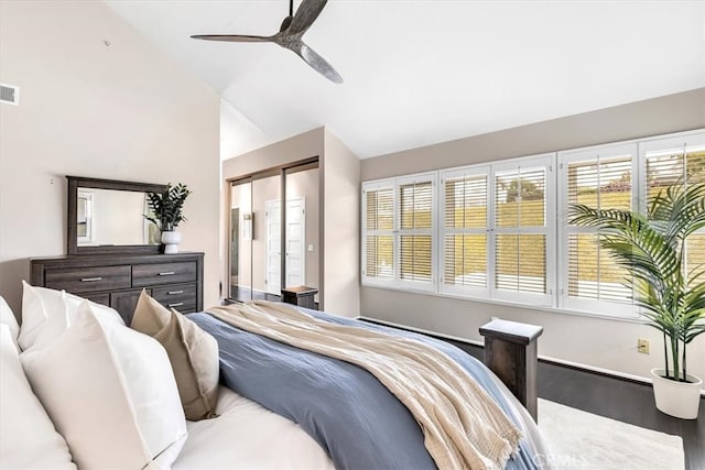 bedroom featuring a ceiling fan, visible vents, vaulted ceiling, and wood finished floors