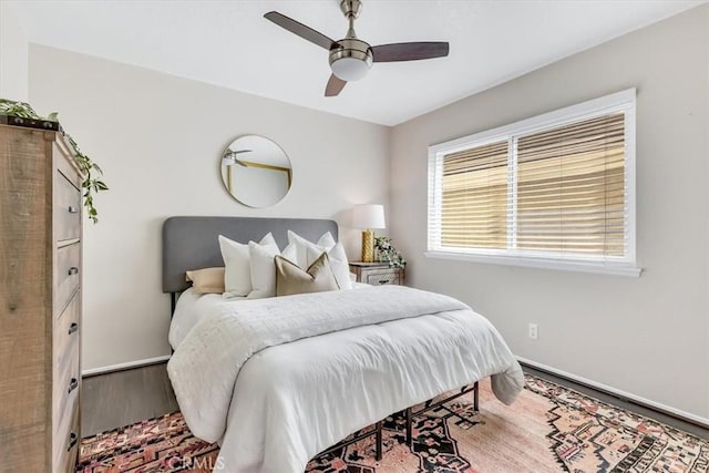 bedroom featuring ceiling fan, baseboards, and wood finished floors