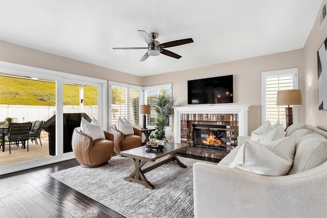 living room with a ceiling fan, visible vents, a fireplace, and wood finished floors