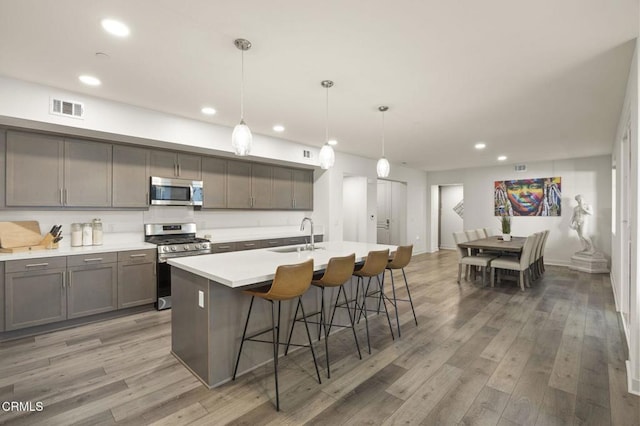 kitchen featuring appliances with stainless steel finishes, gray cabinets, light wood-style floors, a sink, and recessed lighting