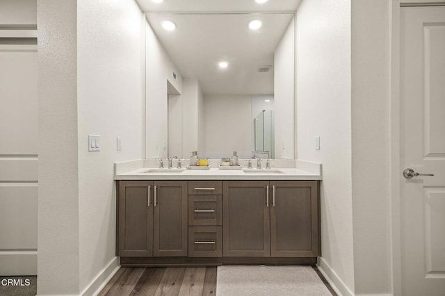 full bath with double vanity, baseboards, a sink, and wood finished floors