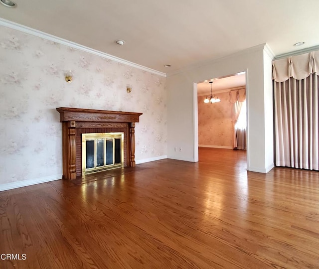 unfurnished living room featuring a chandelier, crown molding, a fireplace, wood finished floors, and wallpapered walls