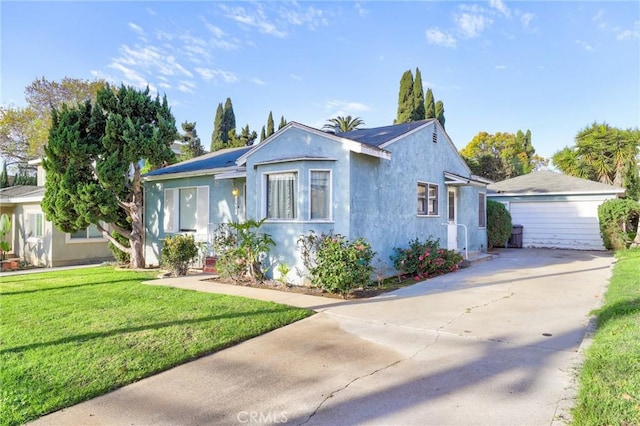 view of front of house with an outbuilding, a front lawn, and stucco siding