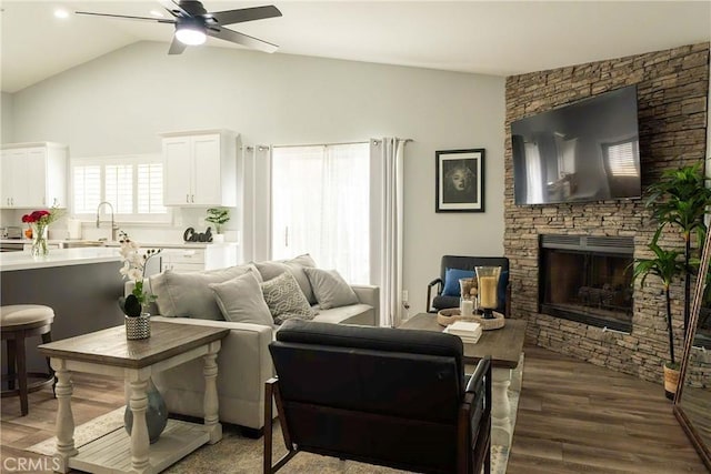 living area with vaulted ceiling, a fireplace, dark wood finished floors, and a ceiling fan