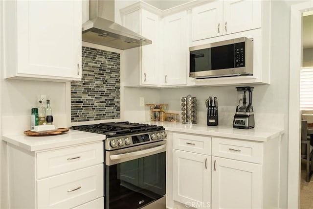 kitchen featuring stainless steel appliances, wall chimney exhaust hood, light countertops, and white cabinets