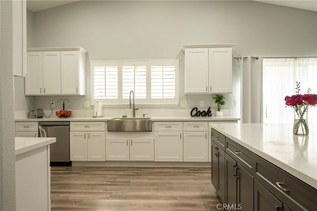 kitchen featuring a sink, white cabinets, dishwasher, and light countertops