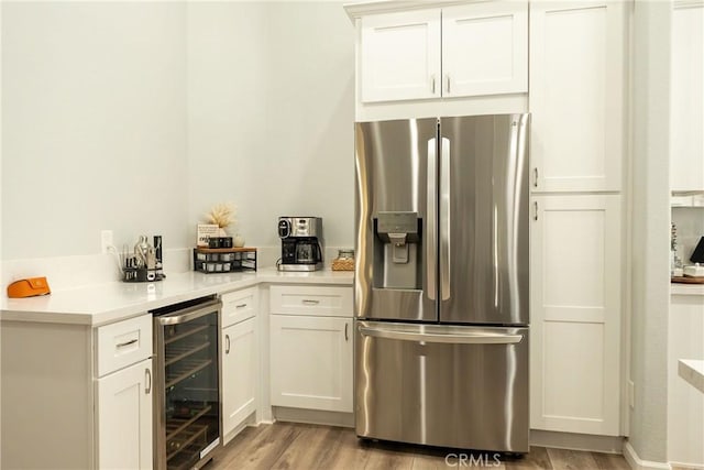 kitchen with wine cooler, light wood-style flooring, white cabinets, light countertops, and stainless steel refrigerator with ice dispenser