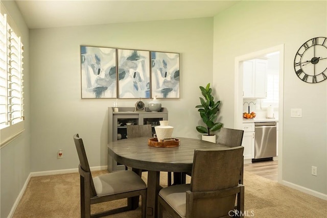 dining area featuring light carpet, vaulted ceiling, and baseboards