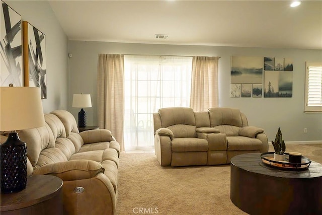 living area with baseboards, visible vents, and light colored carpet