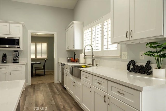 kitchen featuring white cabinetry, stainless steel appliances, a sink, and light countertops