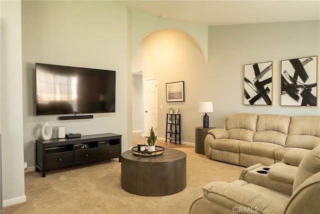 living area featuring carpet, a high ceiling, and baseboards