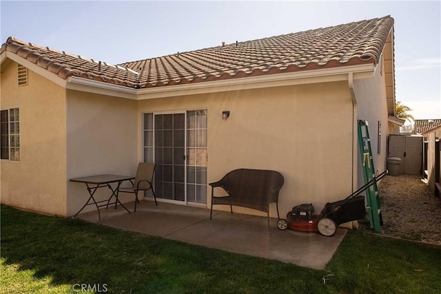 rear view of house featuring a patio, a tiled roof, and stucco siding