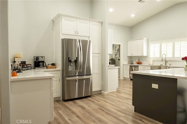 kitchen featuring stainless steel appliances, a sink, light wood-style floors, white cabinets, and light countertops