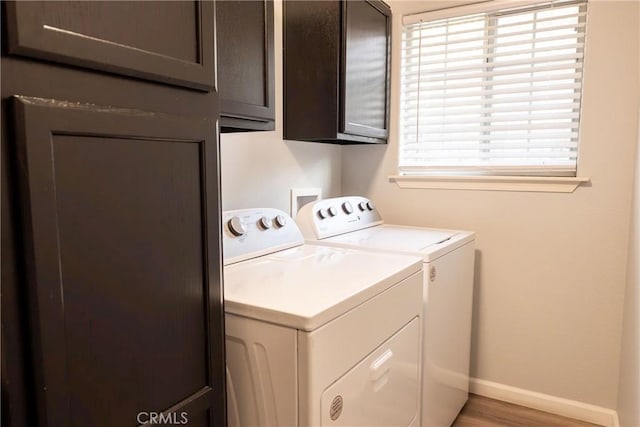 laundry room featuring cabinet space, independent washer and dryer, baseboards, and wood finished floors