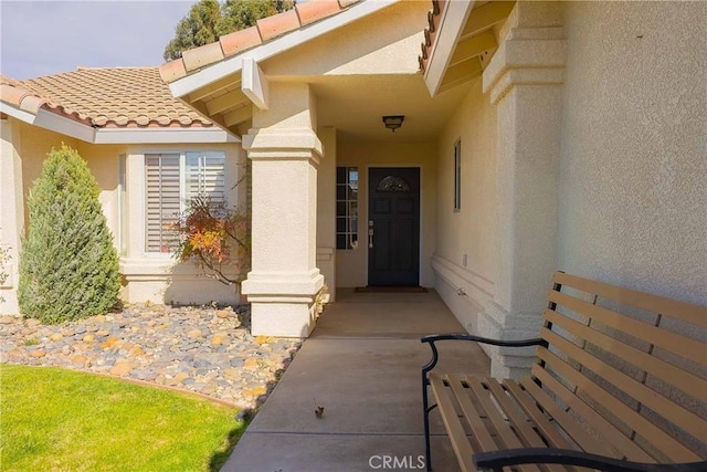 property entrance with a tiled roof and stucco siding