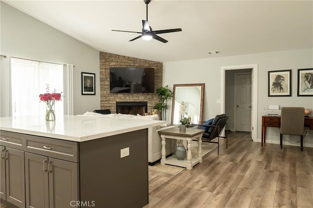 kitchen featuring lofted ceiling, gray cabinetry, visible vents, light wood-style floors, and light countertops