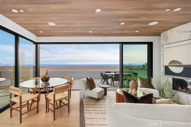 sunroom / solarium featuring wood ceiling, a wealth of natural light, and a high end fireplace