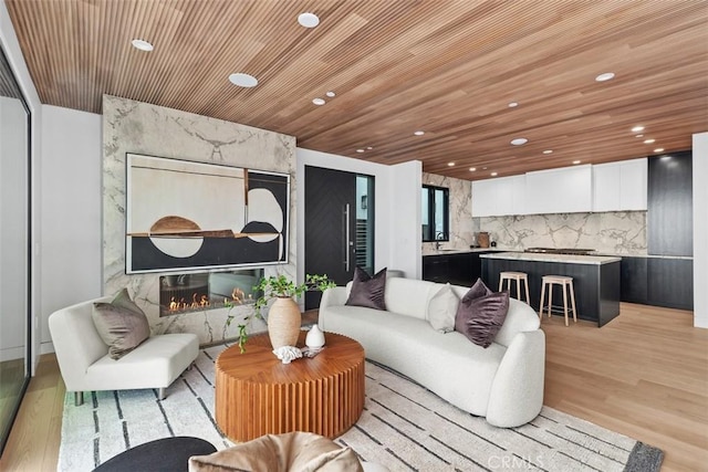 living area with recessed lighting, a fireplace, wood ceiling, and light wood-style floors