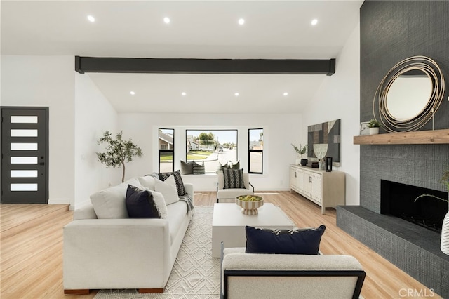 living room featuring light wood-style floors, recessed lighting, a fireplace, and vaulted ceiling with beams