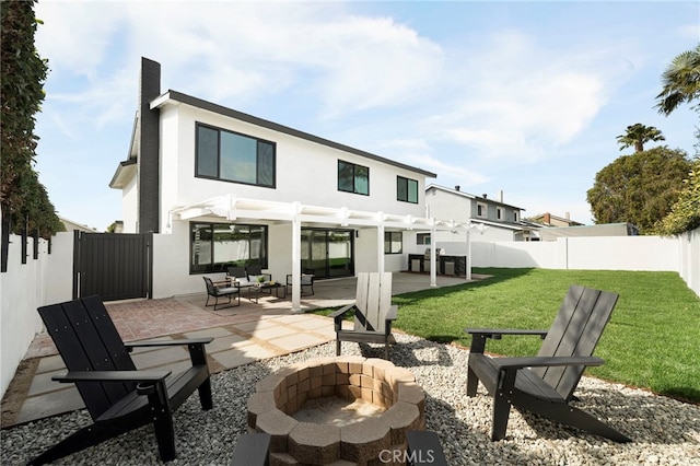 back of house featuring stucco siding, a lawn, a pergola, a fenced backyard, and a fire pit