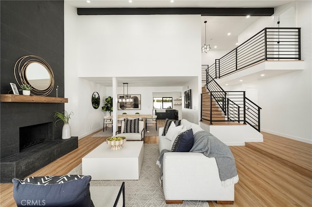 living room with stairs, a large fireplace, baseboards, and wood finished floors