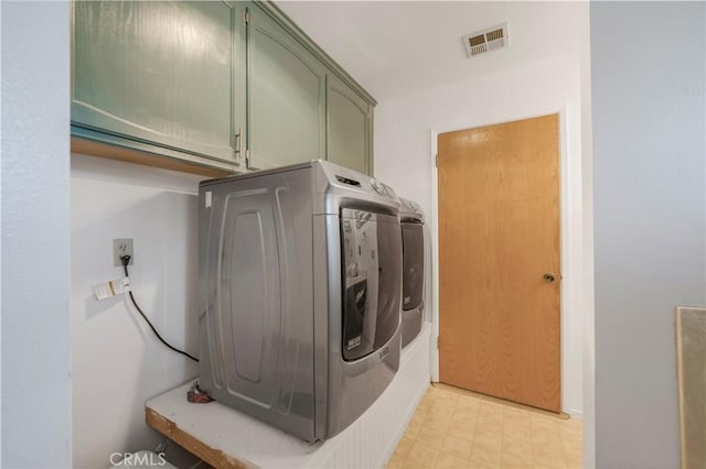 laundry room featuring cabinet space, visible vents, light floors, and washer / dryer