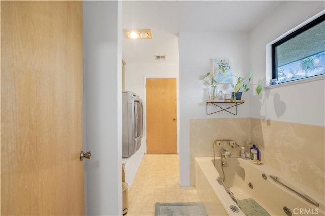 bathroom featuring a whirlpool tub, visible vents, and washer / clothes dryer