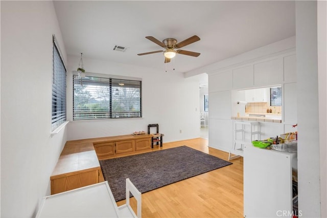 kitchen with visible vents, white cabinets, a ceiling fan, light wood-type flooring, and backsplash