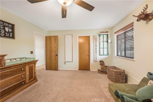 living area featuring carpet floors, a ceiling fan, and baseboards