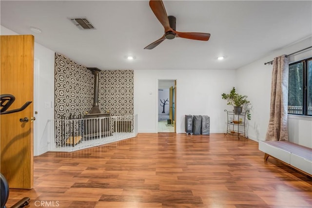 interior space with recessed lighting, wood finished floors, visible vents, a ceiling fan, and a wood stove