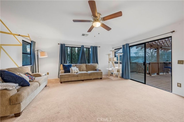 carpeted living area with a healthy amount of sunlight, visible vents, and ceiling fan