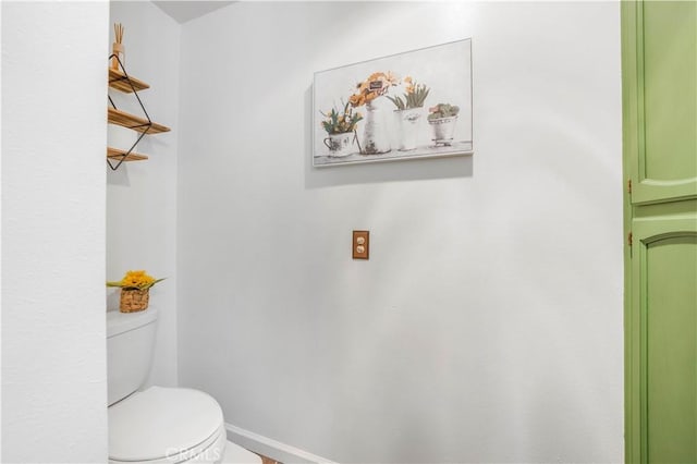 bathroom featuring baseboards and toilet