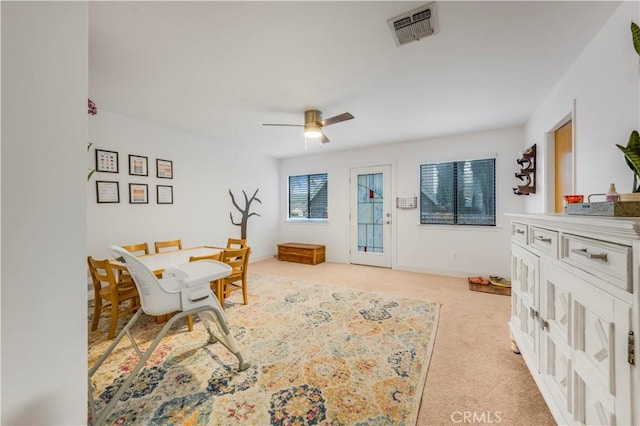 living area with ceiling fan, baseboards, visible vents, and light colored carpet