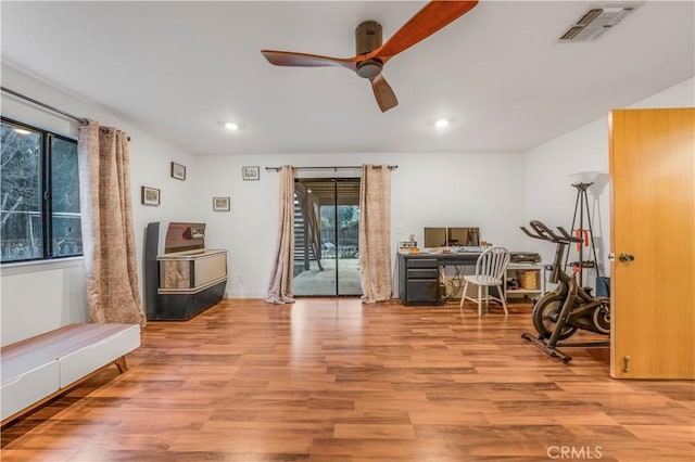 home office with light wood-style floors, a healthy amount of sunlight, visible vents, and ceiling fan