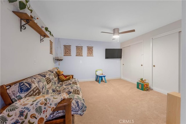 living area featuring carpet, a ceiling fan, and baseboards