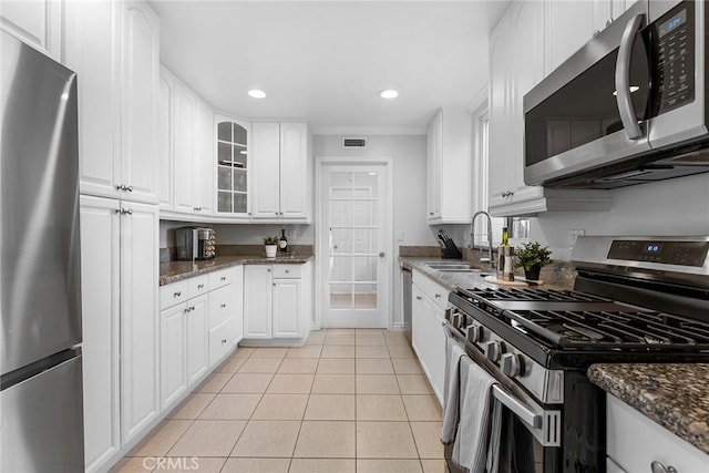 kitchen with light tile patterned flooring, a sink, glass insert cabinets, appliances with stainless steel finishes, and white cabinetry