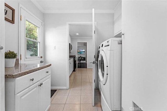 clothes washing area with washer / dryer, light tile patterned flooring, crown molding, and baseboards
