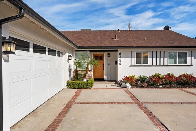 view of front of home featuring stucco siding, concrete driveway, an attached garage, and a shingled roof
