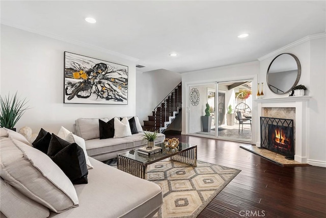 living room with visible vents, hardwood / wood-style flooring, a high end fireplace, crown molding, and stairs
