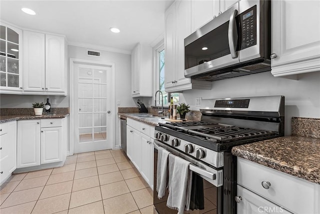 kitchen with visible vents, glass insert cabinets, stainless steel appliances, white cabinetry, and a sink