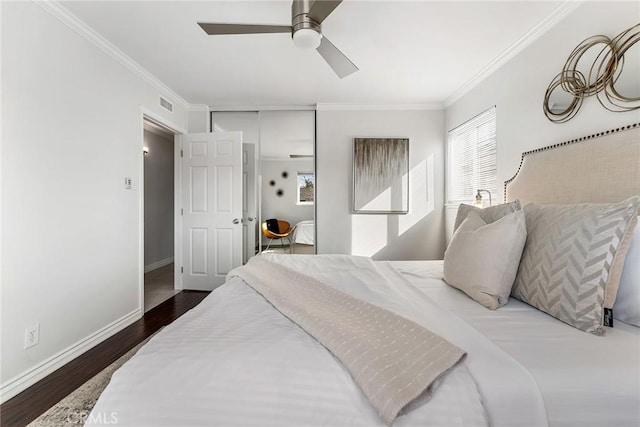 bedroom with visible vents, baseboards, wood finished floors, and crown molding