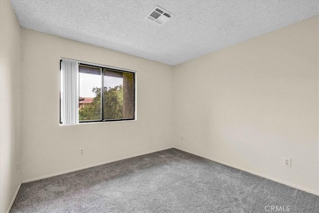 spare room with carpet floors, visible vents, a textured ceiling, and baseboards