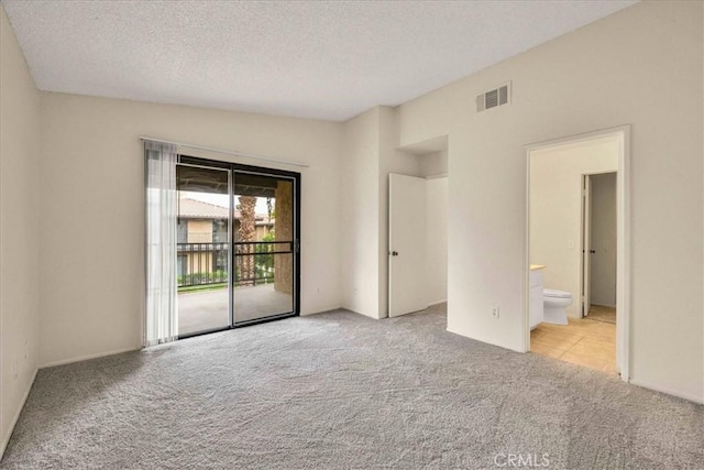 unfurnished room featuring a textured ceiling, visible vents, and carpet flooring