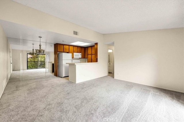 unfurnished living room with light colored carpet, visible vents, vaulted ceiling, and a textured ceiling